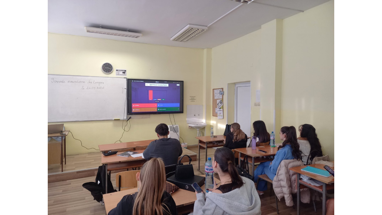 Класна стая, в която група ученици решават куиз, който се представя на голям дисплей