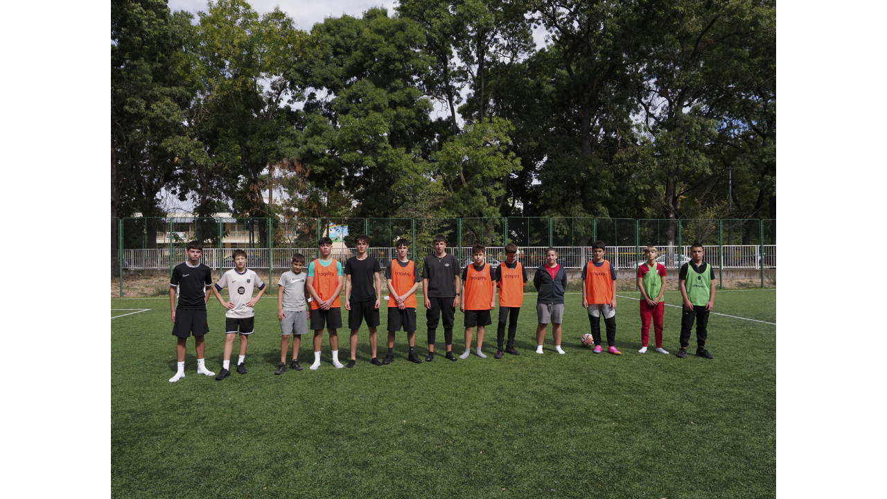 Момчета в спортни екипи, подредени на футболно игрище